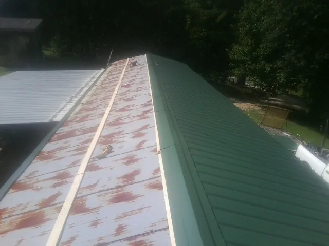 Old rusted panels beside newly installed green metal roofing — Wind Damage Roof Repair by Roofing Brothers in Bixby