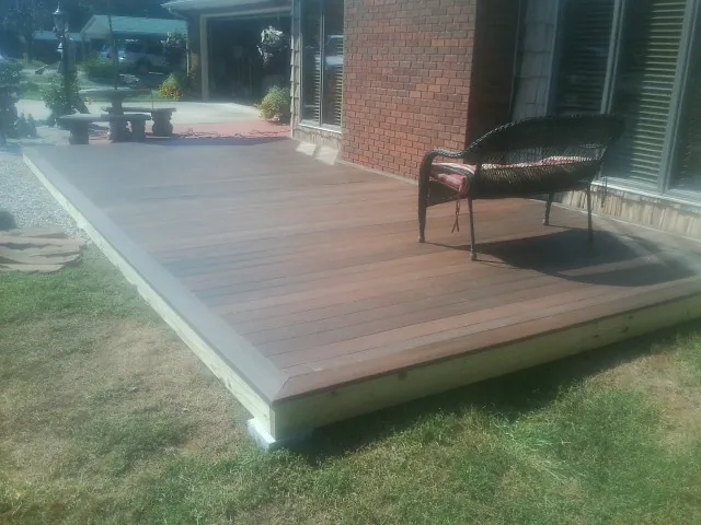 New wood deck and wicker chair beside a brick house in Bixby