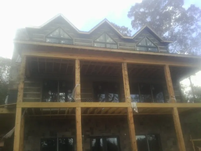 Dormers and porch framing on a large log home under construction — Roof Coating work by our crew in Bixby