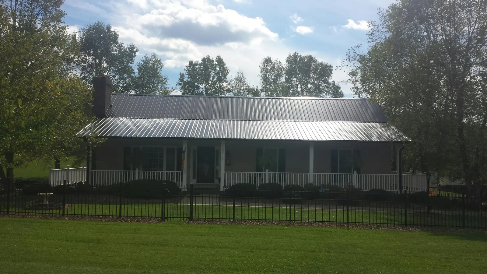 Gray metal roof on a brick ranch with a full width front porch — Gutter Guard Installation work by our crew in Bixby