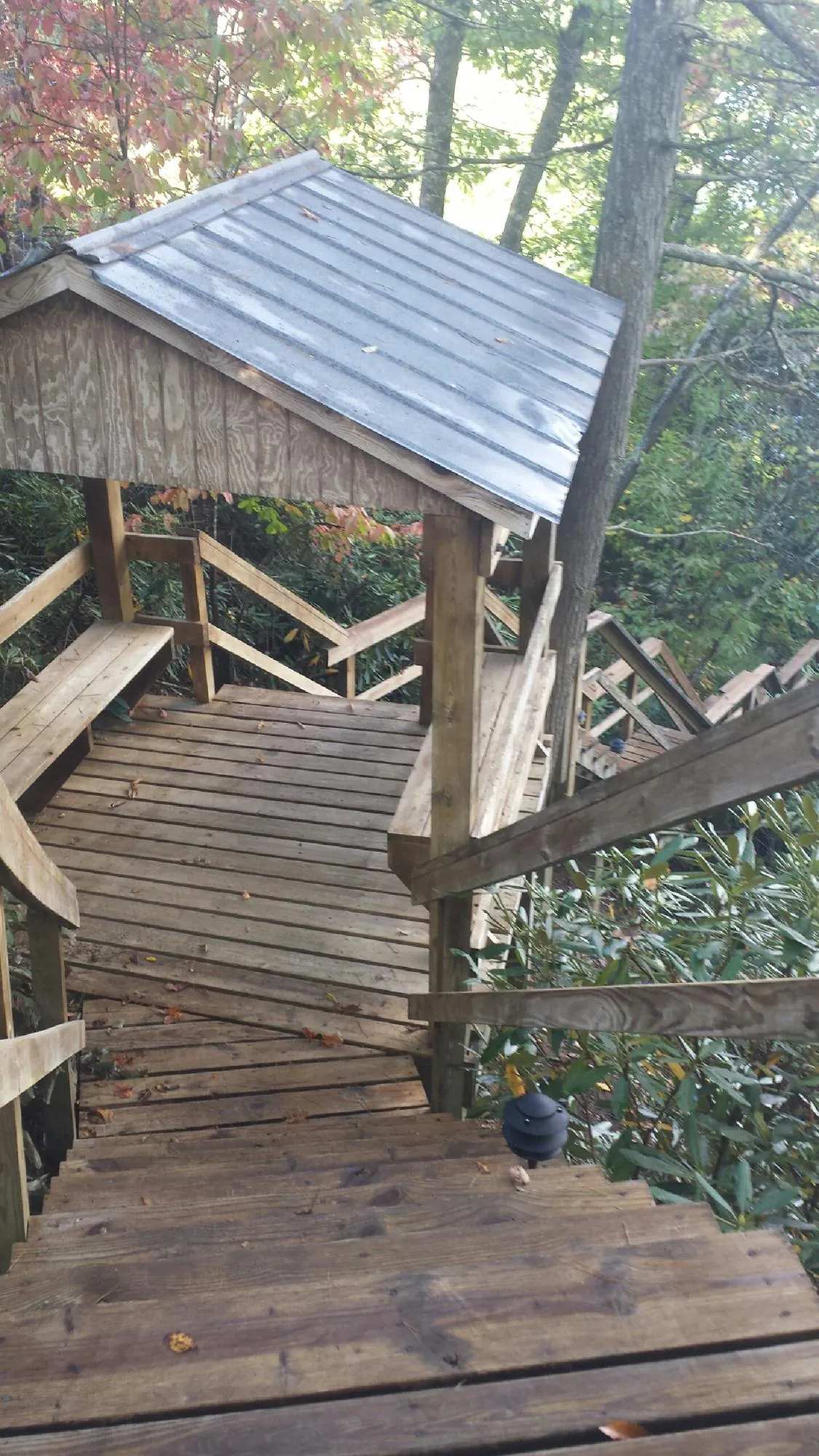 Metal roofed shelter over wooden steps on a wooded walkway — Skylight Repair & Installation work by our crew in Bixby