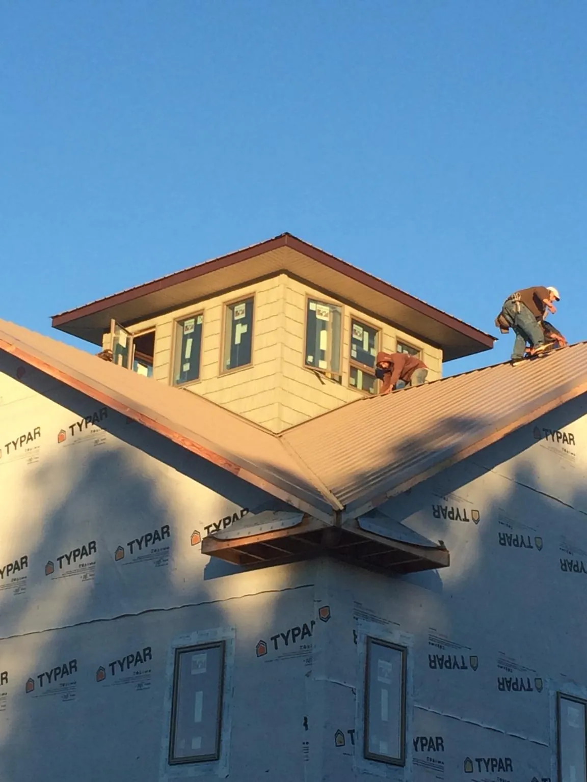 Roofers working around a rooftop cupola on a new metal roof at sunset — Roof Waterproofing in Bixby by Roofing Brothers